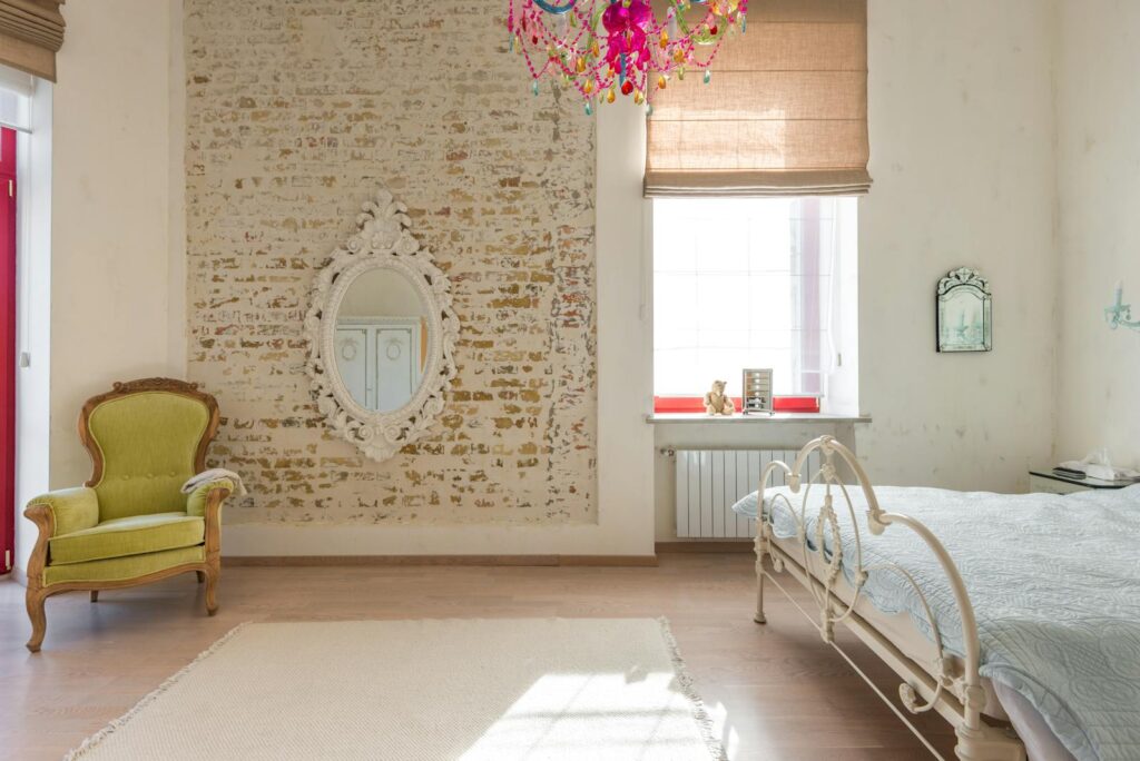 Elegant vintage bedroom featuring a brick wall, ornate mirror, and colorful chandelier.