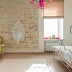 Elegant vintage bedroom featuring a brick wall, ornate mirror, and colorful chandelier.