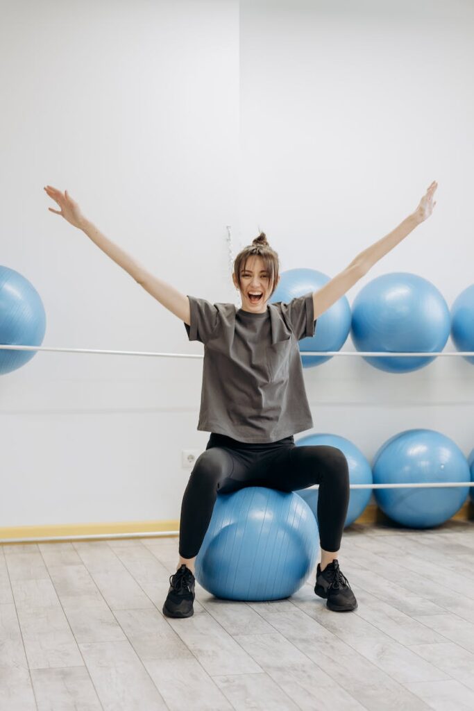 woman sitting on a yoga ball with arms raised